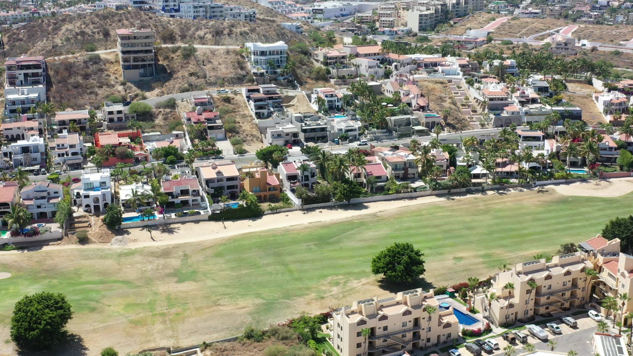 Aerial view of golf fairway, homes, road, and dry hillside.