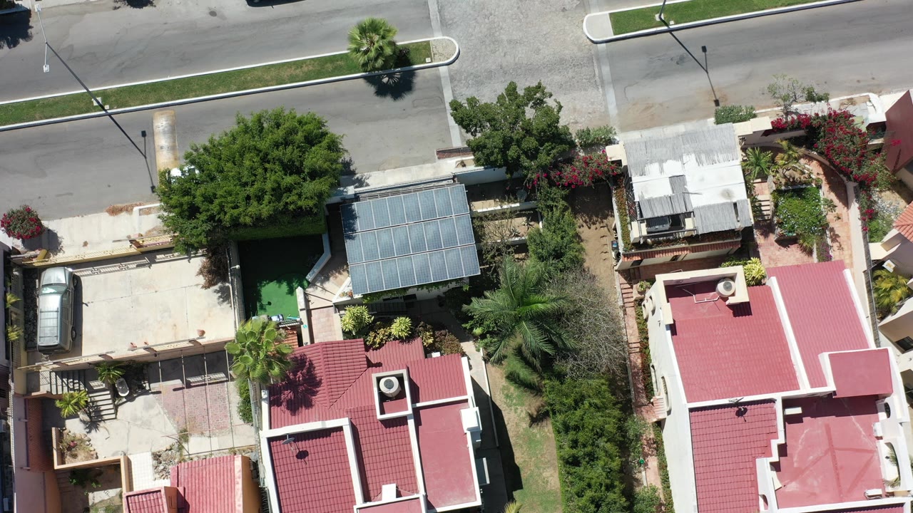 Top-down view of red-roof homes, trees, driveways, and a street.