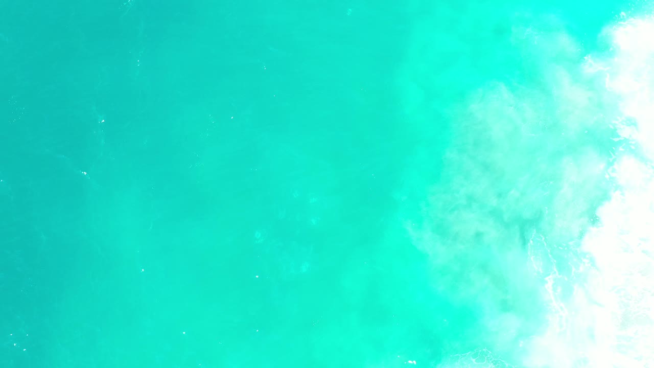 Turquoise ocean water with white surf along the right edge