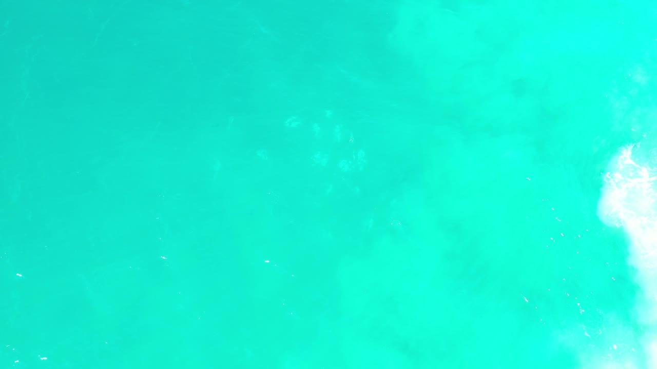 Aqua water field with small surface highlights and surf on the right