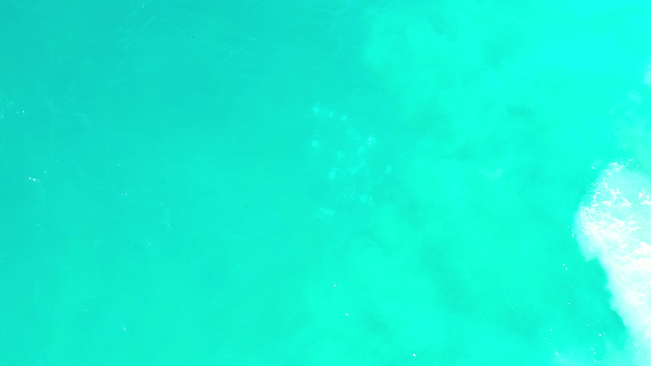 Turquoise ocean water with white foam at the right edge.