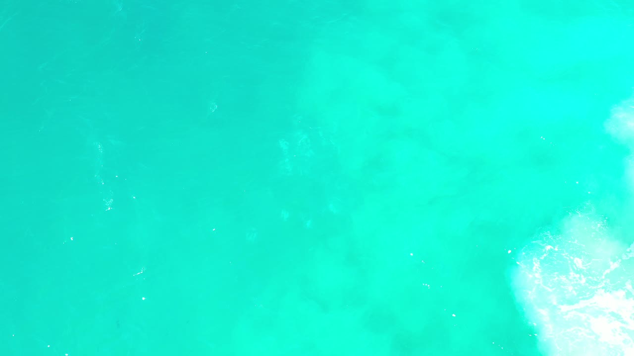 Turquoise ocean water with a small white foam patch near the lower right.