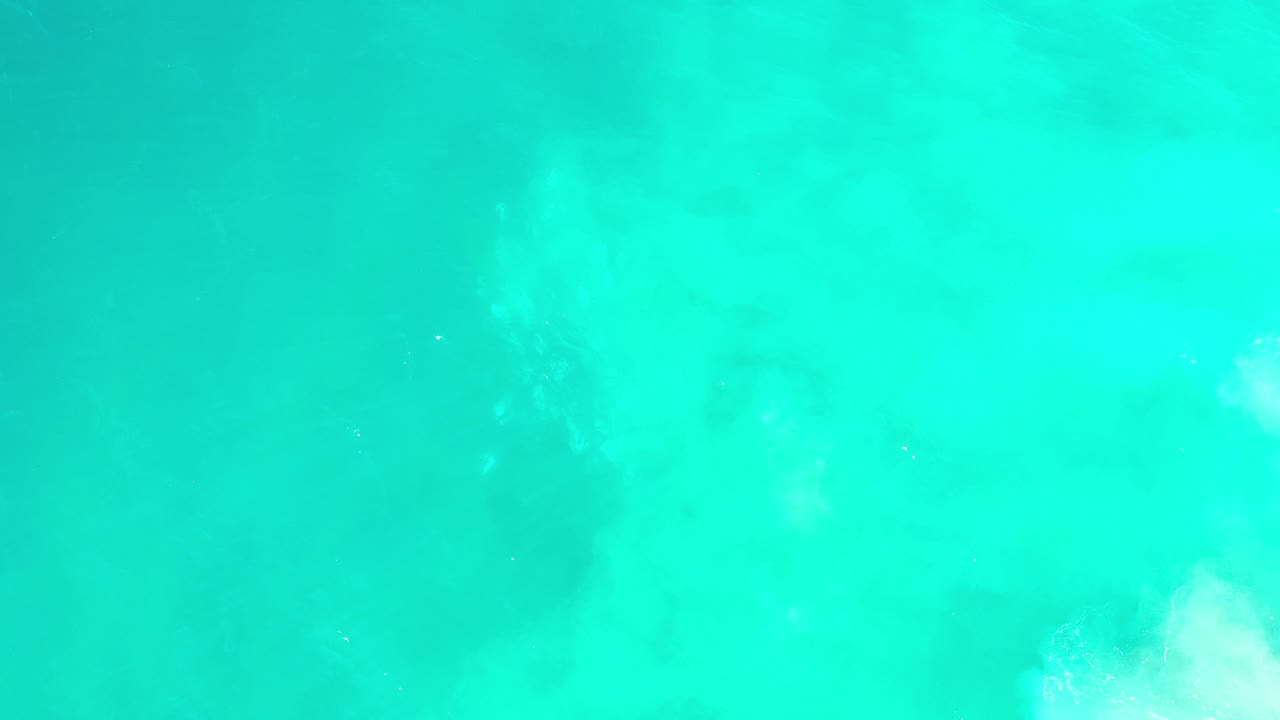 Top-down aerial view of turquoise ocean water in Los Cabos, Mexico, with pale underwater color variation and no visible people.