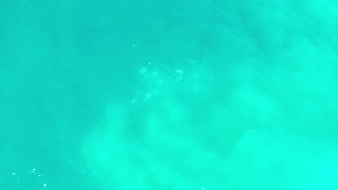 Turquoise-green seawater with soft underwater patches and small ripples.
