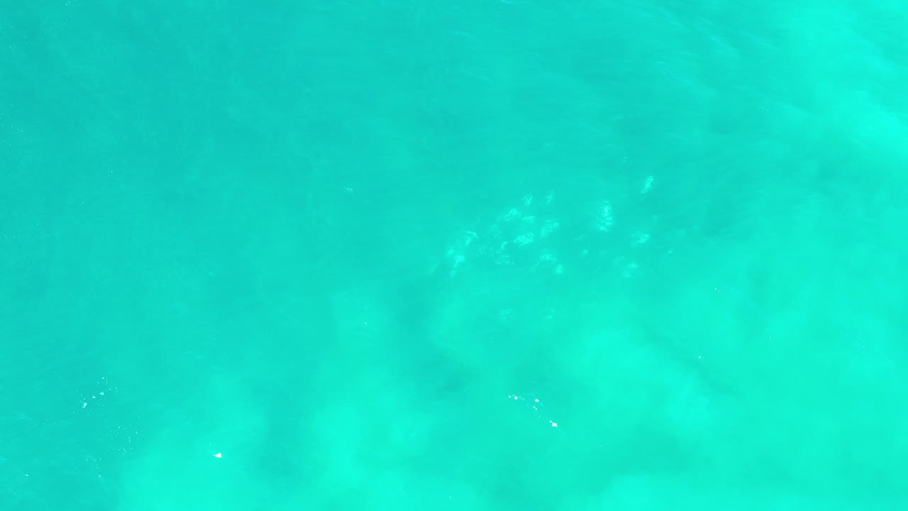 Overhead view of turquoise ocean water in Los Cabos, Mexico, with faint submerged pale patches and no visible people.