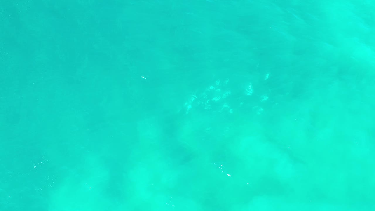 Blue-green sea surface in Los Cabos, Mexico, seen from overhead with subtle ripple marks and no visible people.