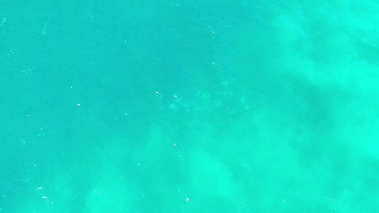 Bright aqua pool water in Los Cabos, Mexico, with pale cloudy patches below the surface and no visible people or objects.