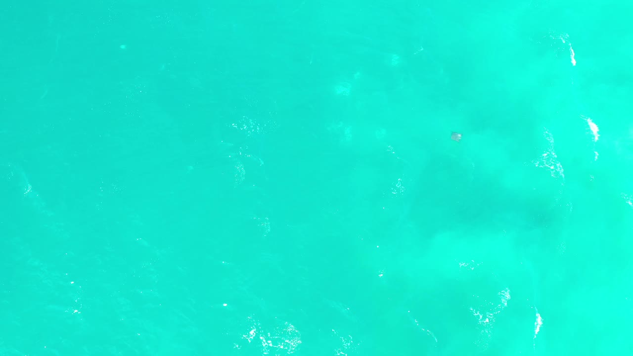 Blue-green sea in Los Cabos, Mexico, seen from above with faint lighter patches beneath the surface and no visible people.