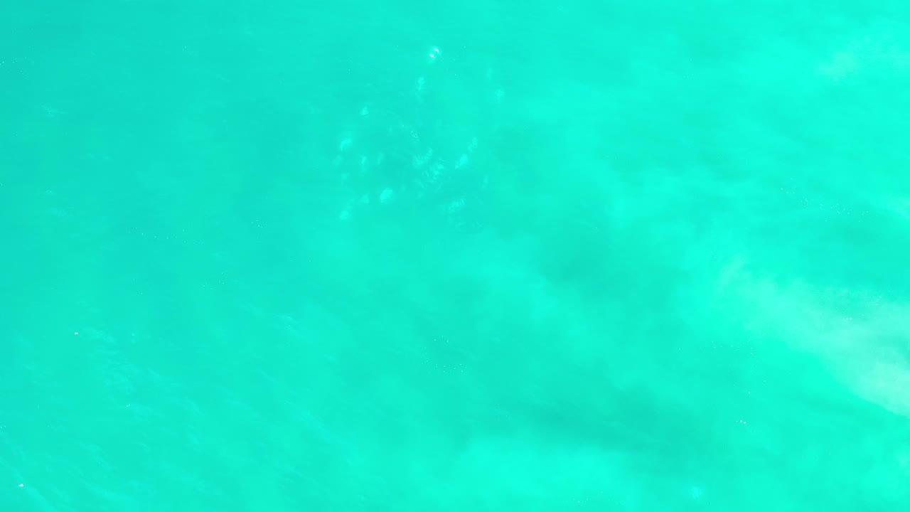 Opening frame of turquoise-green seawater in Los Cabos, Mexico, with soft pale underwater clouding and no visible people.