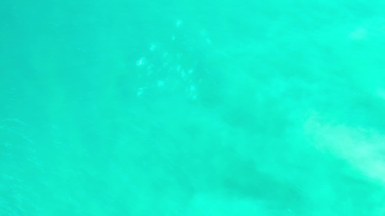 Overhead view of green seawater with soft pale streaks under the surface.