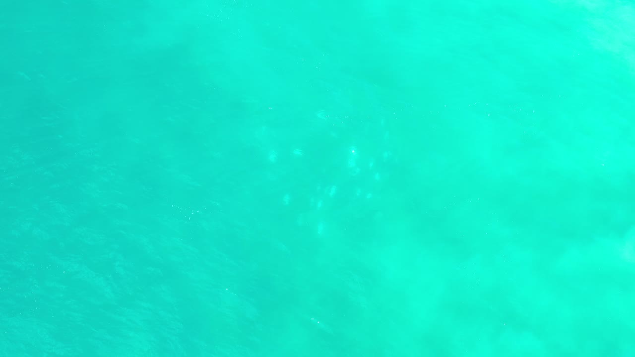 Bright turquoise water fills the frame in Los Cabos, Mexico, with pale cloudy patches beneath the surface and no visible people.