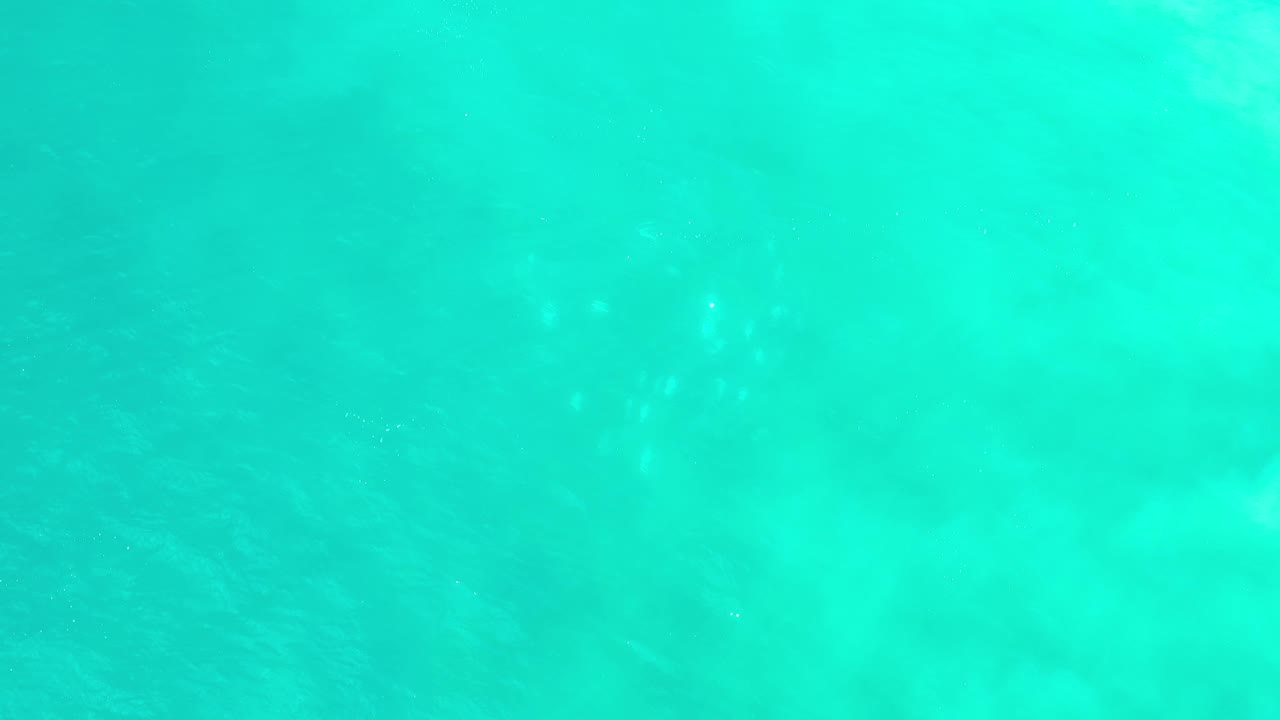 Aqua water in Los Cabos, Mexico, shows gentle ripples and faint sunlight flecks across a mostly open surface, with no visible people.
