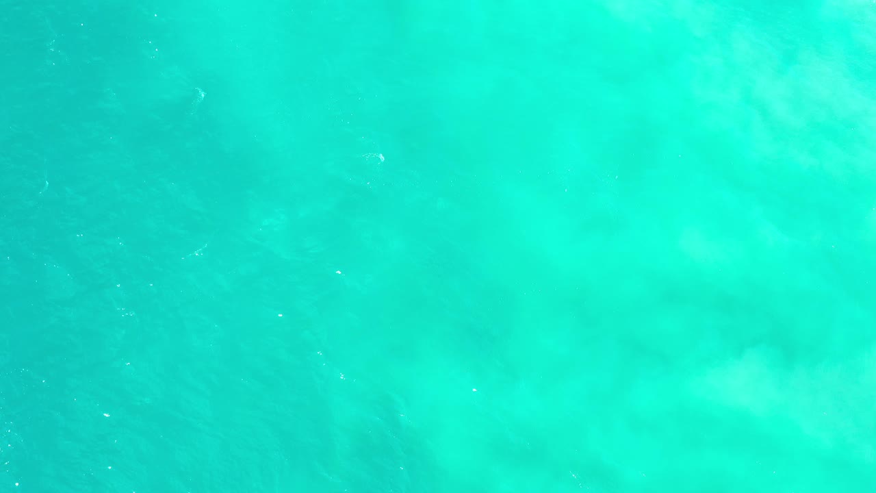 Pale turquoise sea with cloudy underwater color variation.