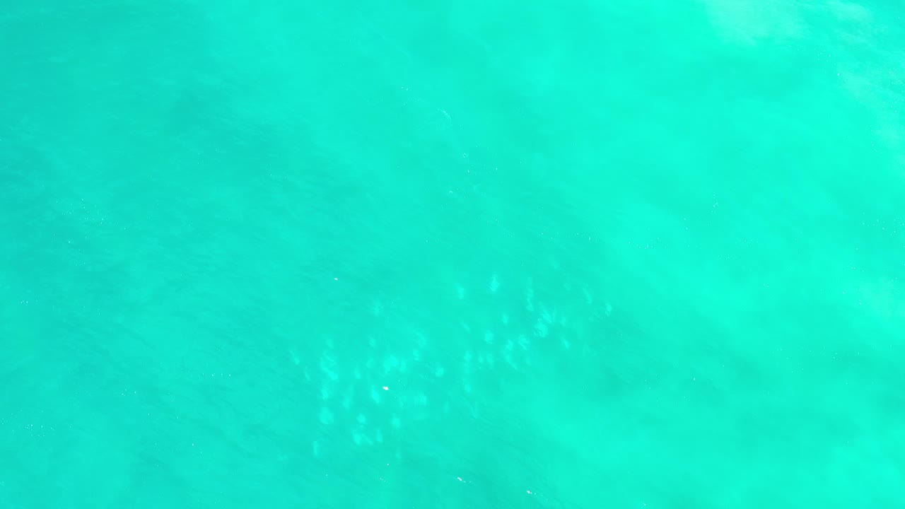 Overhead view of turquoise ocean water in Los Cabos, Mexico, with soft pale underwater patches and no visible people at the start of the clip.