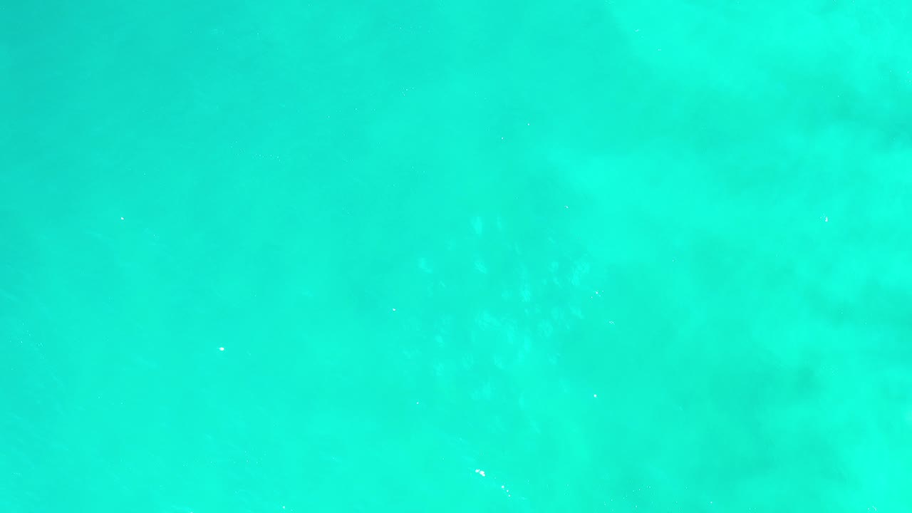 Bird's-eye view of turquoise ocean water in Los Cabos, Mexico, with pale underwater patches and no visible people.