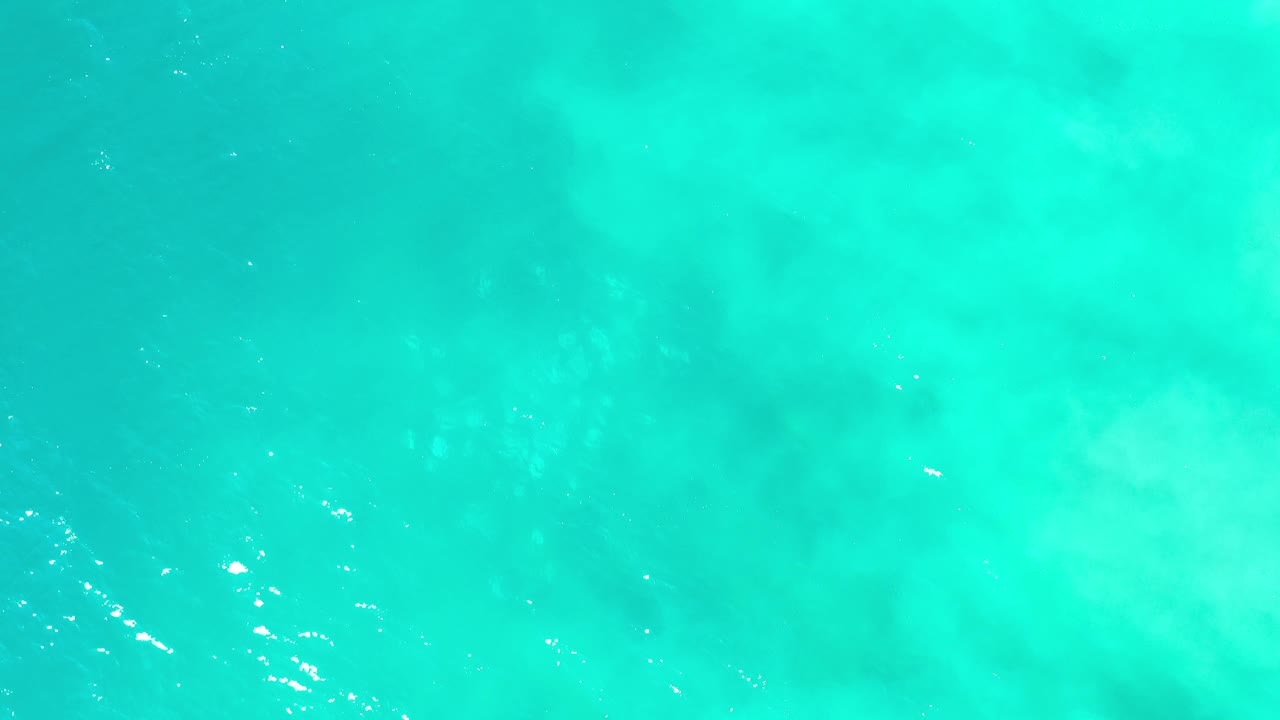 Blue-green ocean surface in Los Cabos, Mexico shows soft ripples and cloudy underwater color variation, with no visible people.