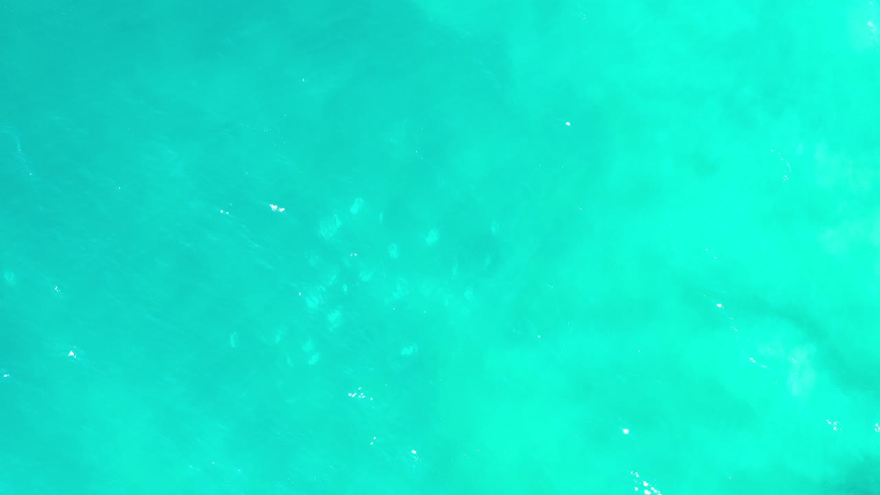 Turquoise-green sea water in Los Cabos, Mexico fills the first frame, with subtle underwater shadows and no visible people.