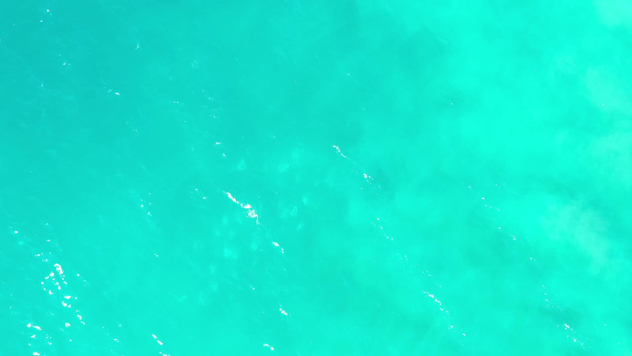 Aqua ocean surface in Los Cabos, Mexico, with soft underwater tonal variation, fine ripples, bright sun flecks, and no visible people.