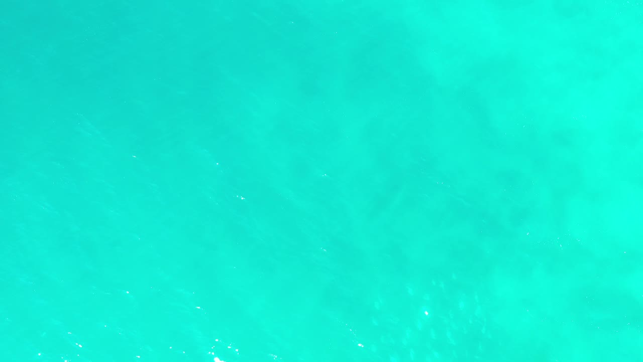 Overhead view of turquoise ocean water in Los Cabos, Mexico, with soft pale underwater patches and no visible people.