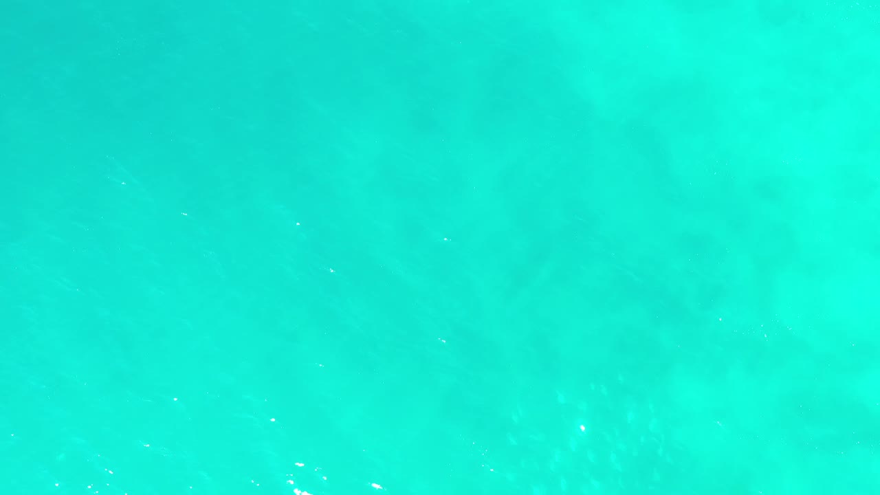 Bright blue-green ocean surface in Los Cabos, Mexico, with scattered white sun reflections and no visible people.