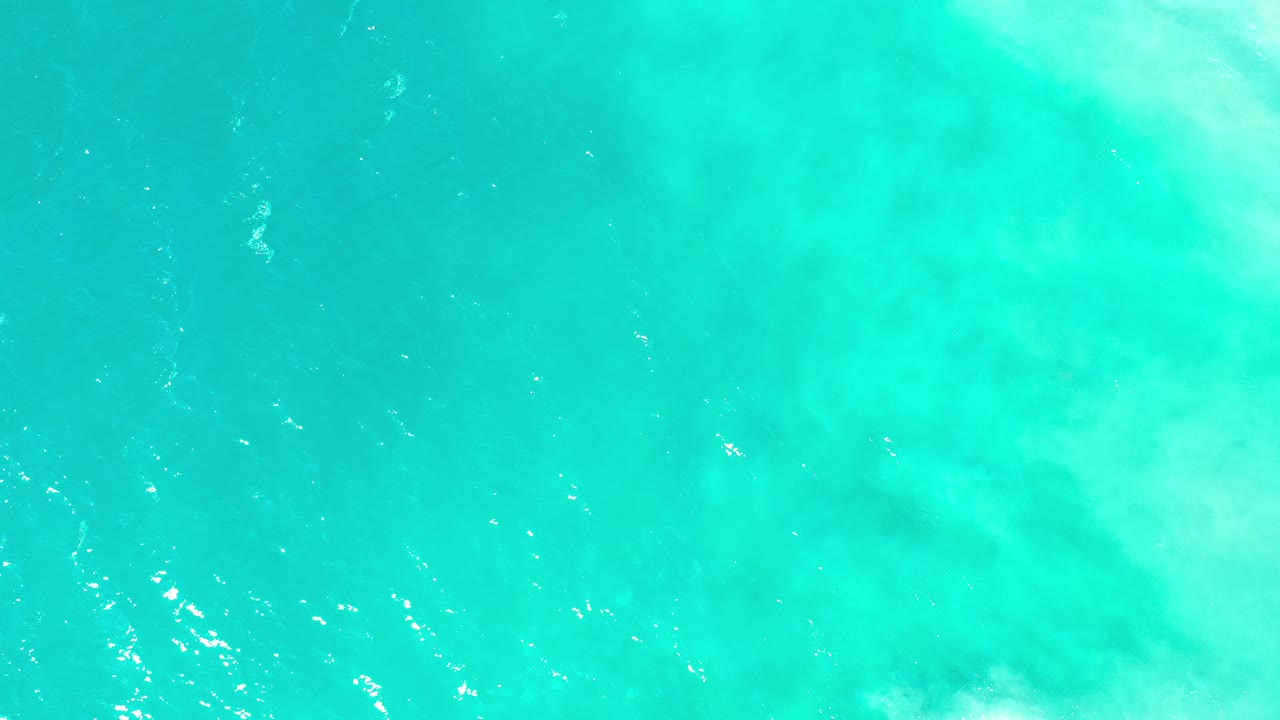 Overhead view of turquoise water in Los Cabos, Mexico, with small white foam marks and no visible people.