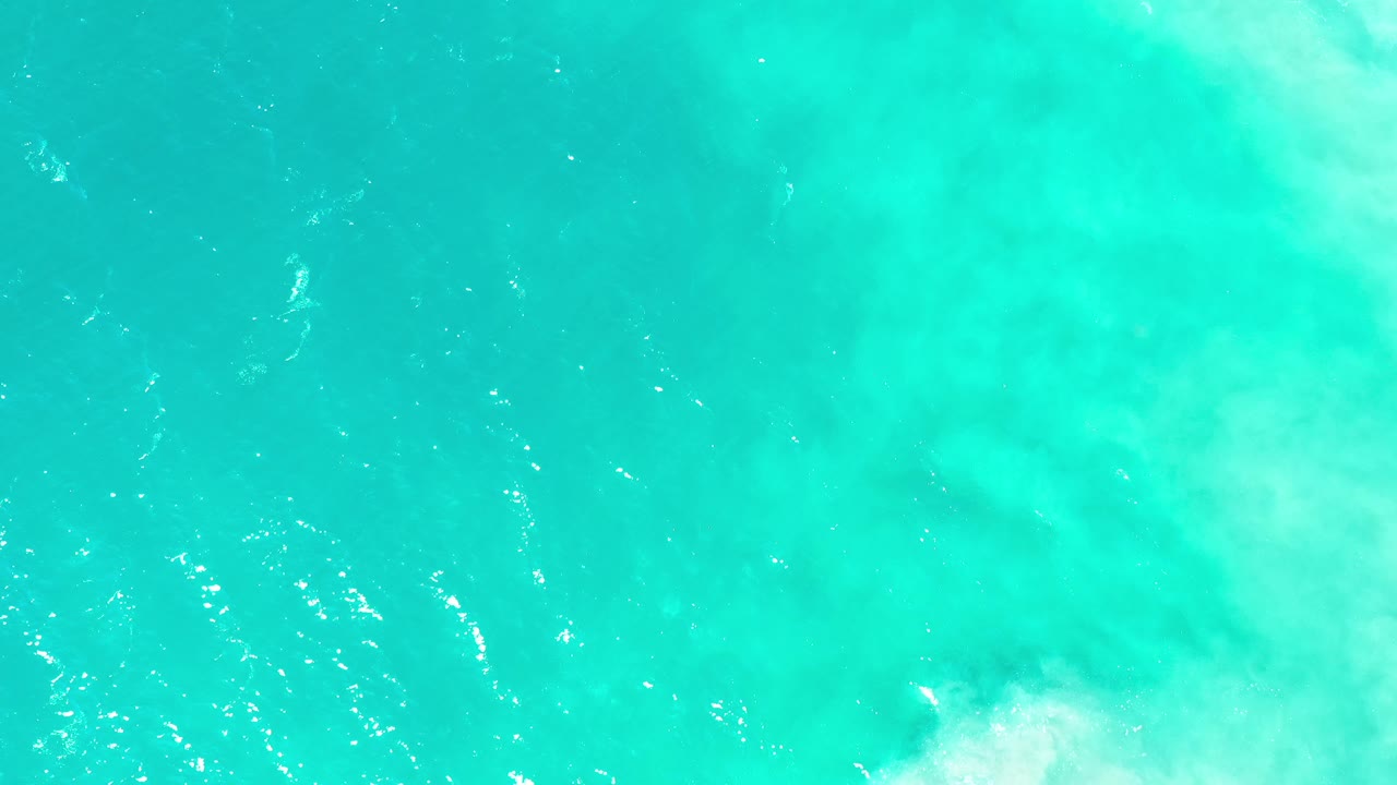 Turquoise sea surface with scattered sparkle and light foam.