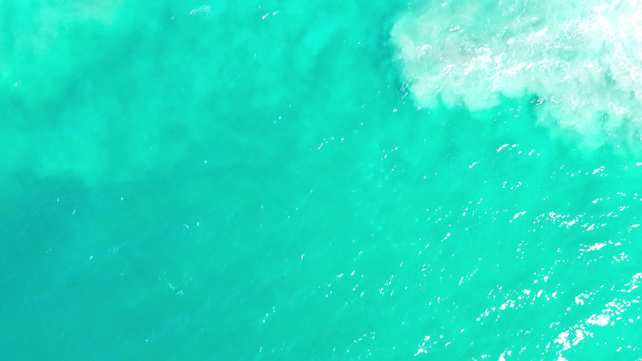 Bright green water with surf foam entering from the top right