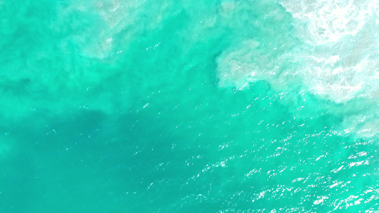 Turquoise ocean water with white foam in the upper right.