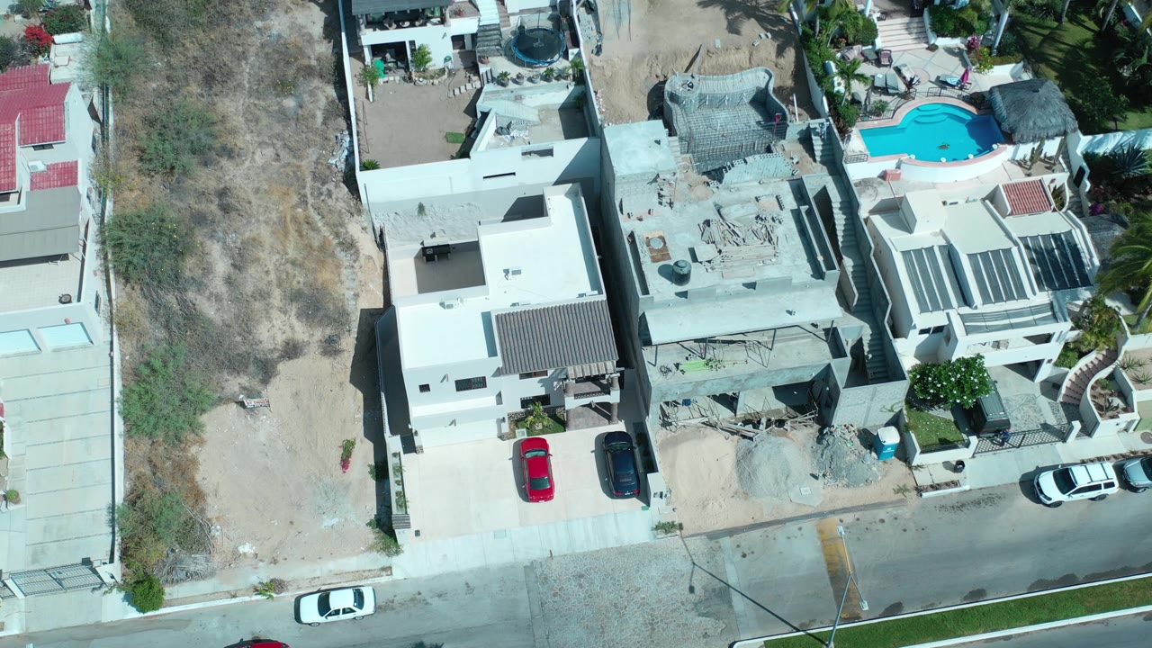 Overhead view of modern homes beside a quiet street and dry lot.