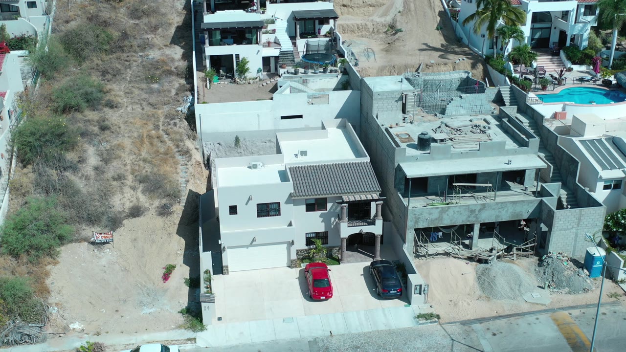 Drone-style view of hillside houses with cars parked in front.
