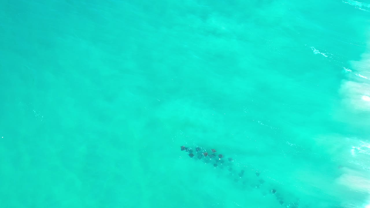 Overhead view of turquoise ocean in Los Cabos, Mexico, with small dark underwater patches and no visible people.