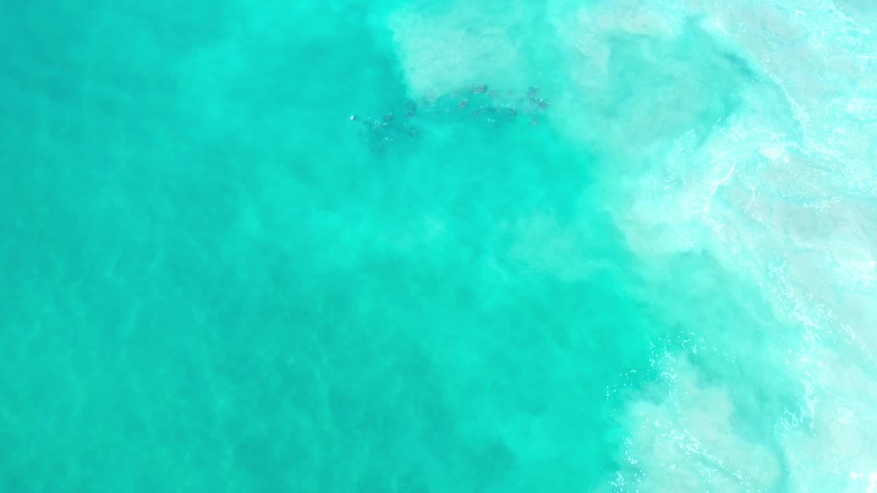 Overhead view of green-turquoise seawater in Los Cabos, Mexico, with pale foam concentrated near the upper right and no visible people.