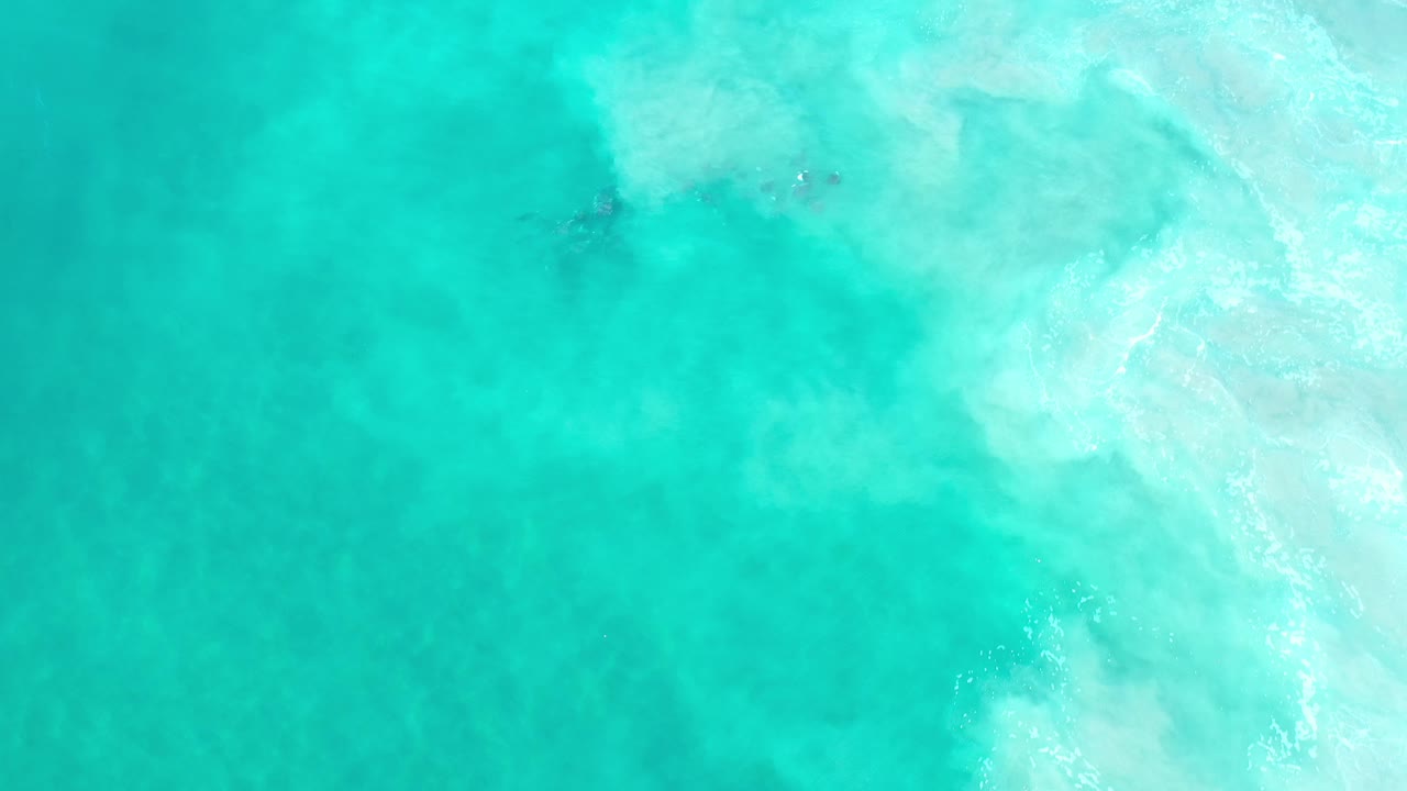 Aerial view of green water with pale breaking surf in the upper right.