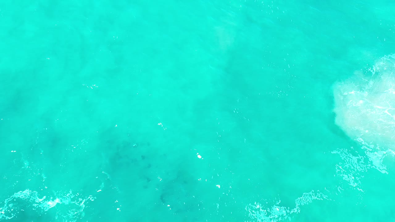 Overhead turquoise water with foam crossing the lower edge.