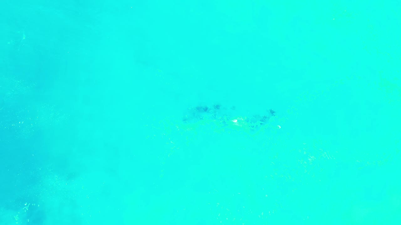 Bright blue-green water with a small dark patch near the top.