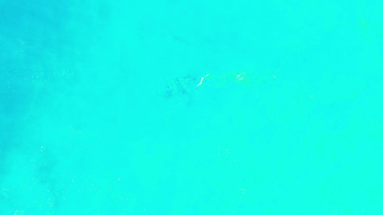 Bright turquoise and light green abstract haze fills the Los Cabos frame at the start, with faint darker patches and no visible people.