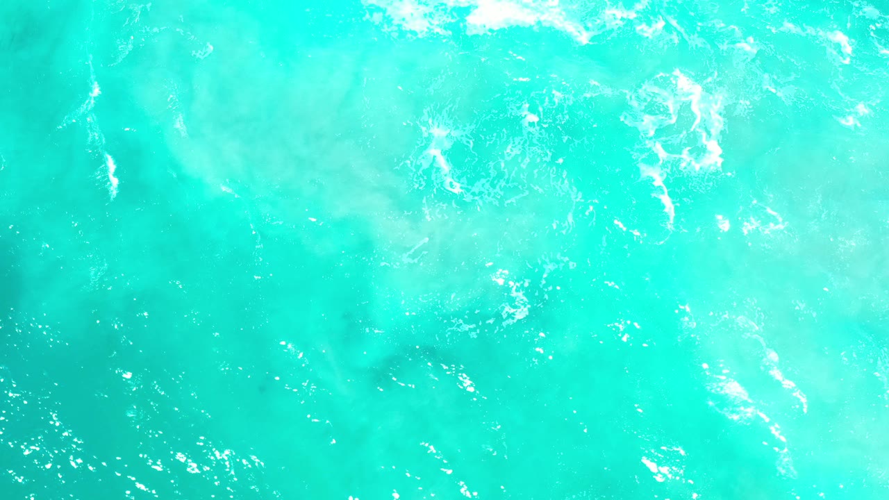 Opening frame of turquoise green ocean surface in Los Cabos, Mexico, with scattered white foam and no visible people.