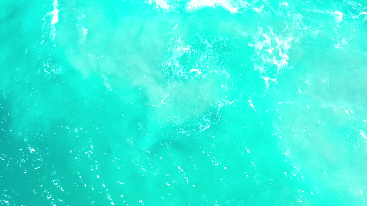Overhead view of turquoise water with scattered white ripples.