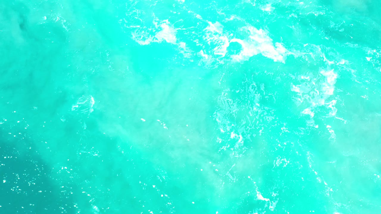Turquoise seawater with white foam ripples.