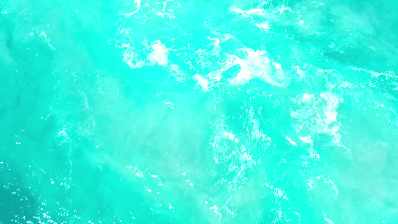Sunlit turquoise water with broken white foam.