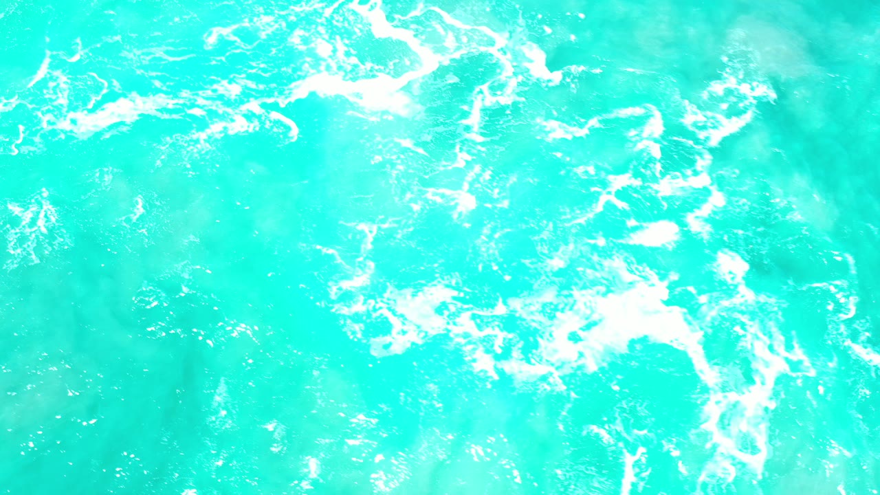 Turquoise ocean surface in Los Cabos, Mexico, with scattered white foam across the upper half and no visible people.