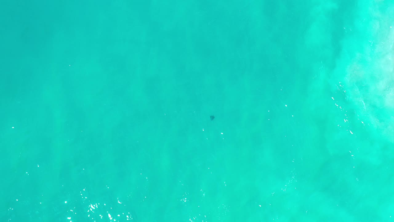 Turquoise ocean water seen from above with pale wave texture.