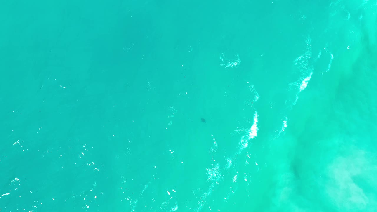 Aqua underwater view in Los Cabos, Mexico, showing faint wave shadows, tiny bubbles, and no visible people.