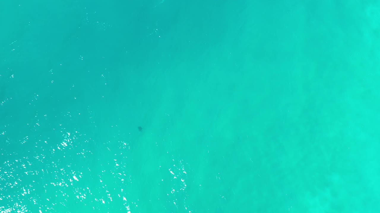 Blue-green ocean surface in Los Cabos, Mexico, with small bright reflections clustered across the water and no visible people.