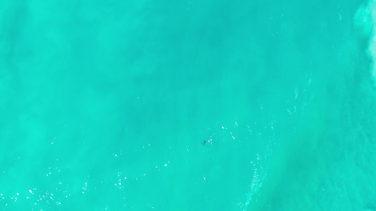 Turquoise ocean seen from above with soft diagonal wave texture.