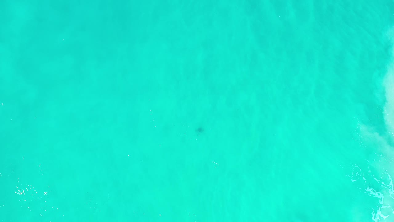 Bright green-blue ocean surface with faint foam marks