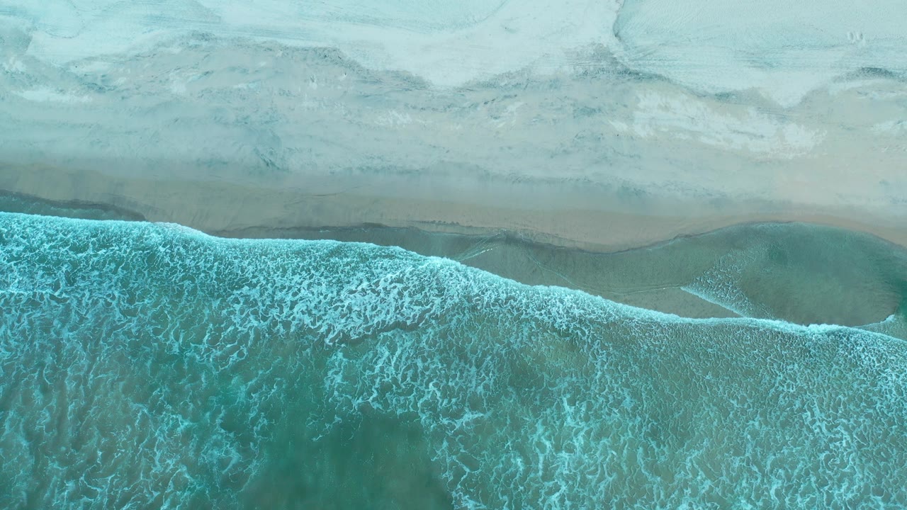 Overhead shoreline with turquoise surf and pale sand