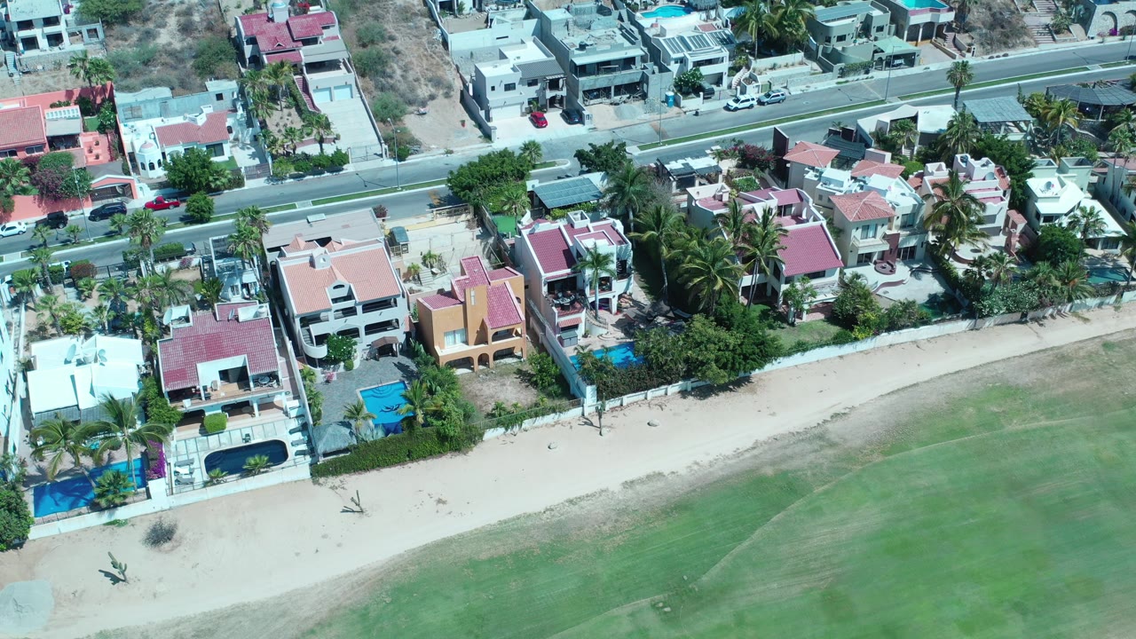 Aerial view of beachfront homes beside shallow green water.