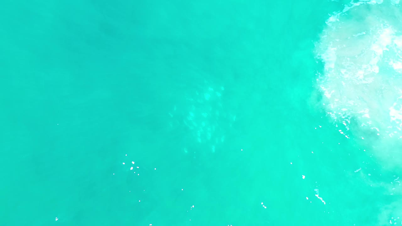 Turquoise water with a bright foamy reflection entering from the upper right.