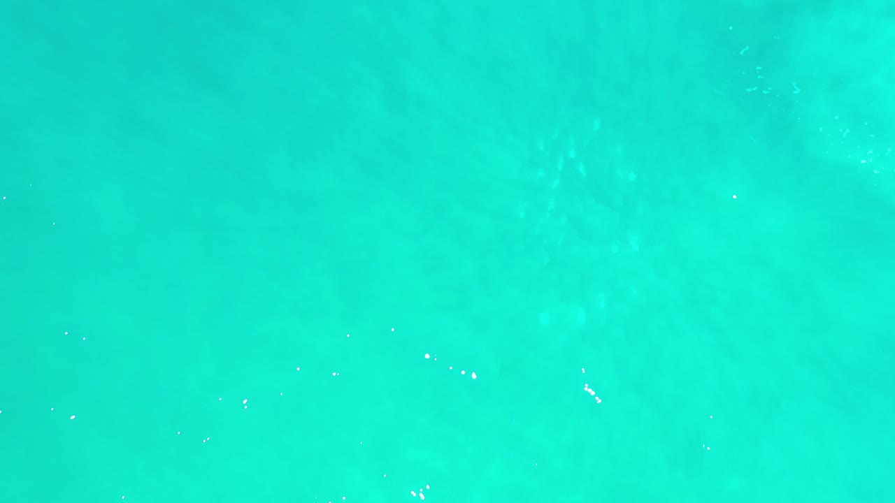 Clear turquoise sea fills the frame in Los Cabos, Mexico, with subtle darker shapes under the surface and no visible people.